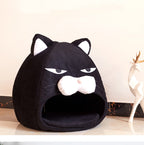 Black pet bed shaped like a cat face on a light wooden floor.