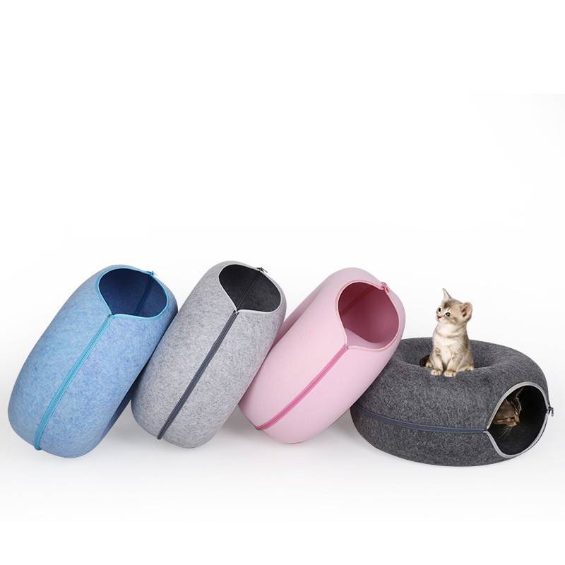Four pet beds in blue, gray, pink, and black on a white background with a cat inside one of the beds.